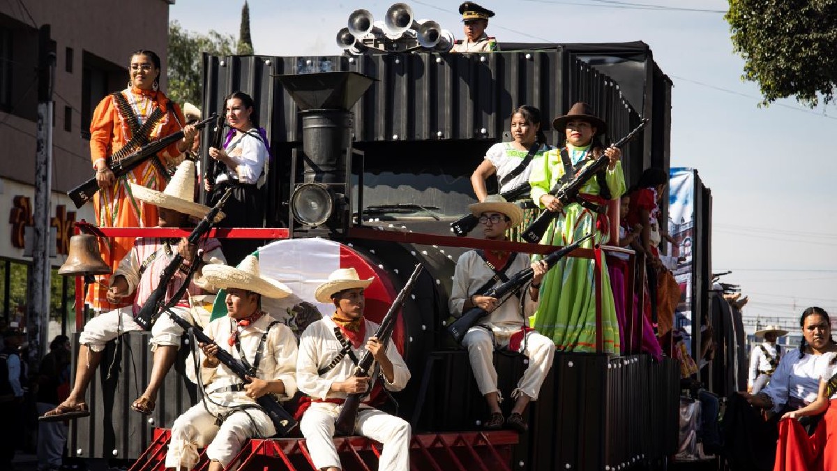 Una carroza de desfile que simula un tren. Varios actores vestidos como 