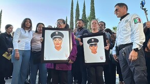 Familiares y colegas de policías de Jalisco rinden homenaje. Mujeres en el centro sostienen dos retratos de oficiales de policía caídas en un ambiente de triste