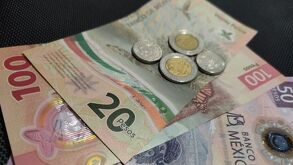 Billetes nacionales de 20, 50 y 100 pesos y un par de monedas nacionales, representando el salario mínimo de México.