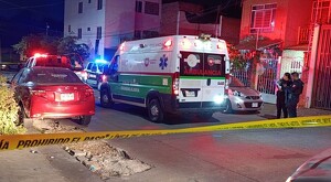 Ambulancia de la Cruz Verde de Guadalajara y patrullas de la Policía de Guadalajara dentro del área acordonada de noche con autos y casas alrededor