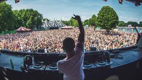 Dj tocando desde un escenario ante miles de personas.