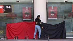 Una mujer de espaldas, con un trapo rojo y negro, en la entrada de la sucursal del Nacional Monte de Piedad. Esto podría ser una protesta por una huelga sindica