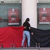 Una mujer de espaldas, con un trapo rojo y negro, en la entrada de la sucursal del Nacional Monte de Piedad. Esto podría ser una protesta por una huelga sindica