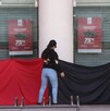 Una mujer de espaldas, con un trapo rojo y negro, en la entrada de la sucursal del Nacional Monte de Piedad. Esto podría ser una protesta por una huelga sindica