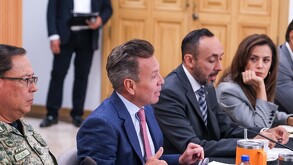 El político Pablo Lemus habla en una mesa de trabajo flanqueado por otros funcionarios, incluyendo una mujer, en una sala con paredes de madera.