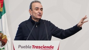 Hombre de edad adulta hablando frente a un micrófono.