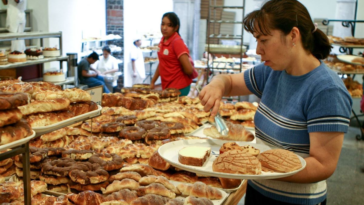 Una mujer elige varias piezas de pan en un negocio.