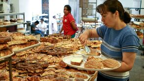 Una mujer elige varias piezas de pan en un negocio.