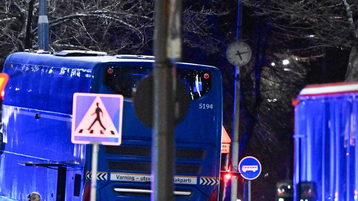 Camión de color azul estacionado frente a una parada de autobuses al lado de varios árboles