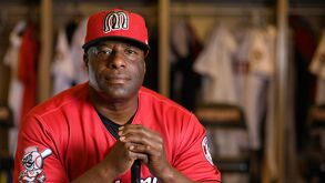 Hombre con uniforme de beisbol sosteniendo un bat.