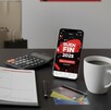 Una mesa con un planificador, una calculadora, una taza de café y un móvil que muestra el logo de 
