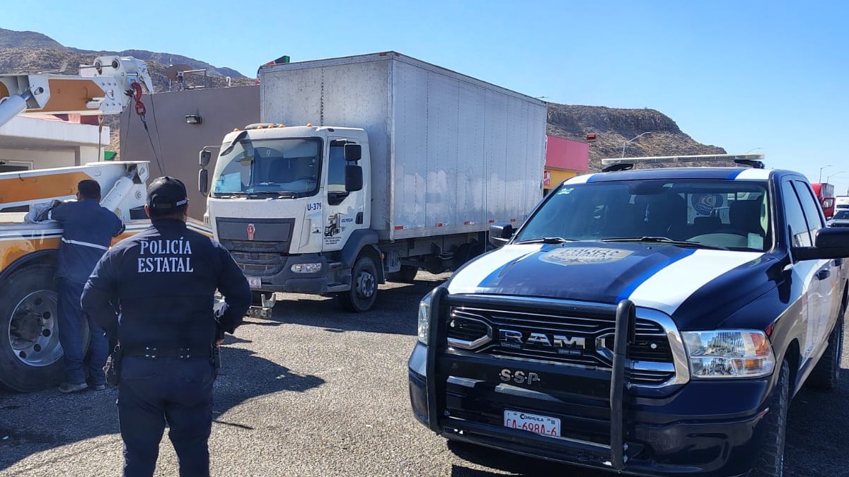 Patrulla de Coahuila y un tráiler en color blanco en una carretera con un cerro de fondo