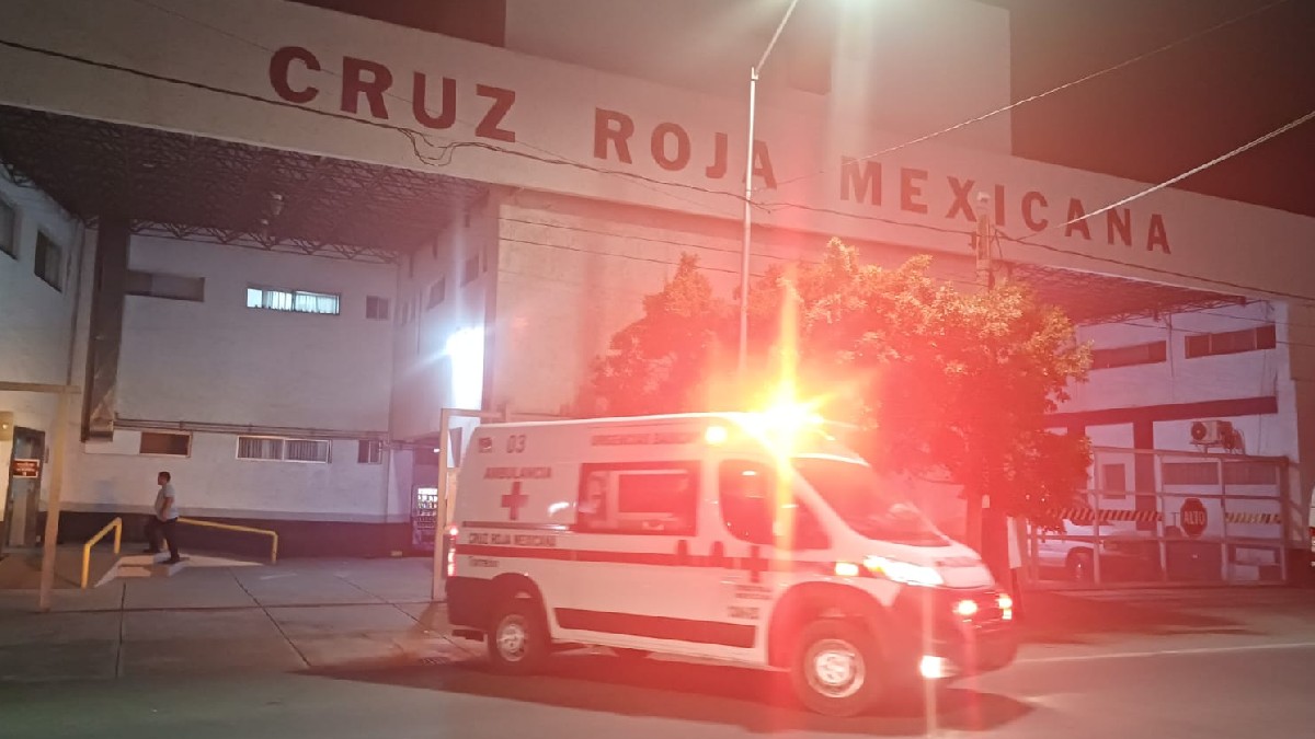 Foto de Cruz Roja Mexicana por fuera de noche y con luces rojas de la ambulancia.