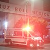 Foto de Cruz Roja Mexicana por fuera de noche y con luces rojas de la ambulancia.