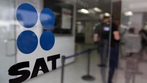 Oficina de SAT por fuera, con personas borrosas al fondo.