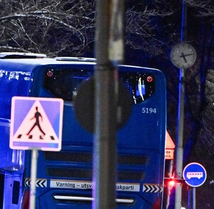 Camión de color azul estacionado frente a una parada de autobuses al lado de varios árboles