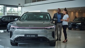 una pareja viendo un auto byd king en una agencia