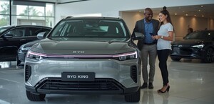 una pareja viendo un auto byd king en una agencia