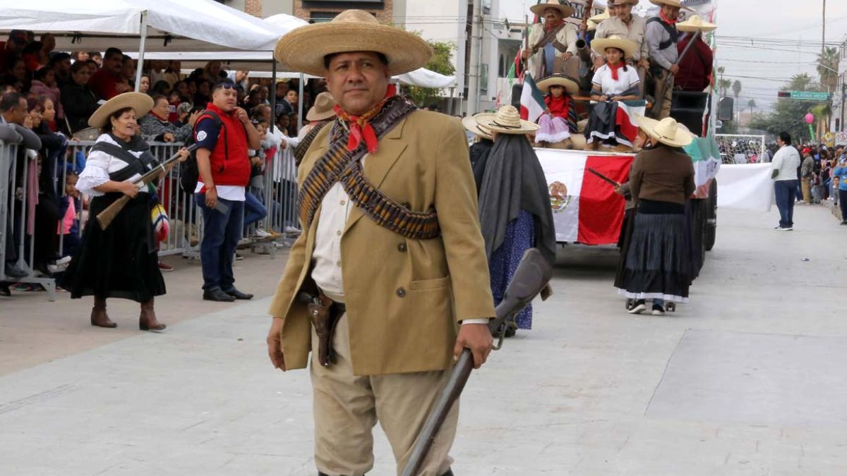 Grupo de personas vestidas con atuendos característicos de la Revolución Méxicana en el desfile de Torreón.