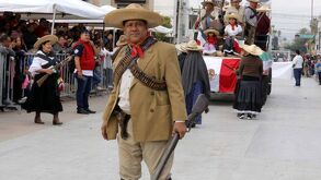 Grupo de personas vestidas con atuendos característicos de la Revolución Méxicana en el desfile de Torreón.