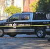 Vista lateral de una Patrulla de la Policía Municipal de Guadalajara estacionada sobre la calle y detrás de una cinta policiaca
