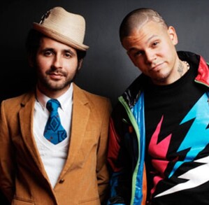 Integrantes de calle 13 al lado de mural de una niña y un niño