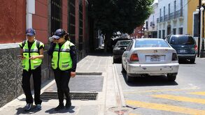 Dos mujeres encargadas de vigilar que los autos respeten el funcionamiento de los parquímetros en Puebla.