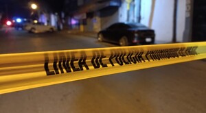 Cinta policiaca amarilla acordonando la calle donde el joven motociclista fue asesinado durante la madrugada. Un automóvil negro detrás