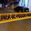 Cinta policiaca amarilla acordonando la calle donde el joven motociclista fue asesinado durante la madrugada. Un automóvil negro detrás
