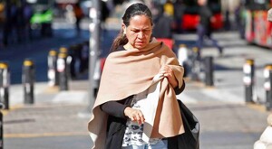 Señora caminando en calles de Guadalajara vistiendo una reboso para cubrirse debido al frío durante un día soleado