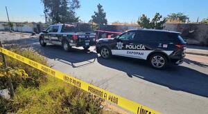 Dos patrullas de la Policía Municipal de Zapopan dentro de un área acordonada con cinta policiaca en el lugar donde un hombre fue asesinado