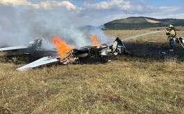 Avioneta incendiándose y bombero apagándola con manguera