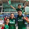 Familia mexicana vistiendo playeras de la Selección Mexicana a las afueras del Estadio Akron en Guadalajara con multitud de personas de fondo