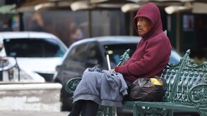 un hombre abrigado en la banca de un parque en puebla