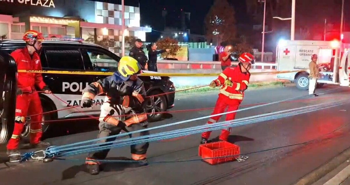 Elementos de Protección Civil y Bomberos de Zapopan tirando del sistema de cuerdas frente a una patrulla de la Policía Zapopan y una ambulancia de la Cruz Roja