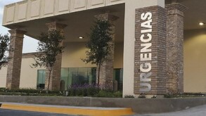 Se observa un edificio gris con un letrero grande que dice urgencias.