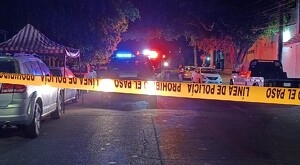 Patrulla de policía y ambulancia de Guadalajara detrás de una cinta policiaca acordonando el área de la agresión con autos a los costados