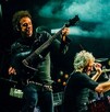 Gustavo Cerati, Charly Alberti y Zeta Bosio miembros de Soda Stereo tocando instrumentos en concierto