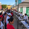 Un módulo de registro del Programa de Vivienda para el Bienestar en México, con personas haciendo fila para registrarse, personal de Conavi atendiendo en mesas
