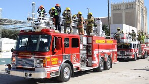 Dos camiones de bomberos circulan sobre la avenida Matamoros en la Plaza Mayor durante desfile de la Revolución en Torreón. Teatro Isauro Martínez de fondo.