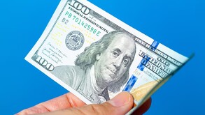 Persona agarrando un dólar estadounidense.