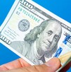 Persona agarrando un dólar estadounidense.