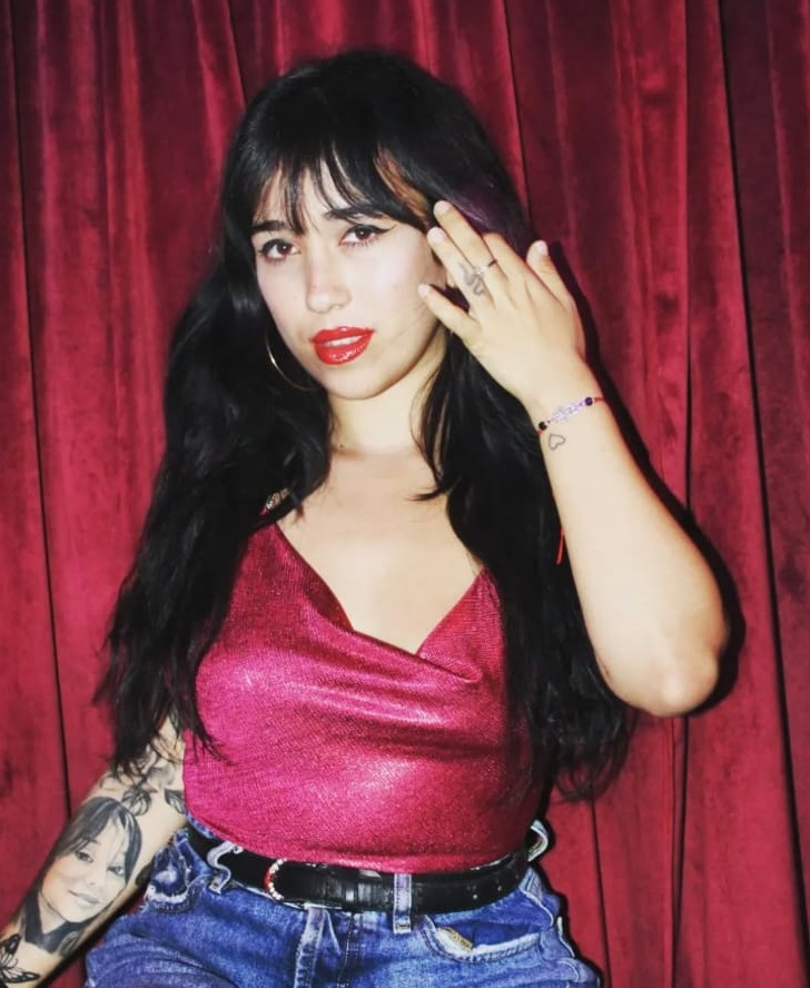 Mujer joven con blusa escotada, sosteniendo su cabello para una foto.