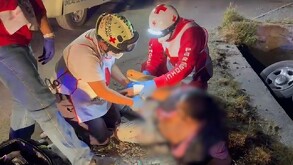 Paramédicos de la Cruz Roja atienden a un hombre que se encuentra tirado en el piso  y a un costado se observa una llanta de una camioneta que cayó a un canal.