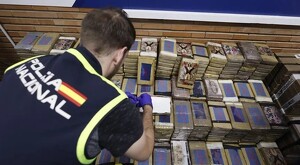 Elemento de la Policía Nacional de España frente a varios paquetes de droga que fueron incautadas durante el operativo internacional