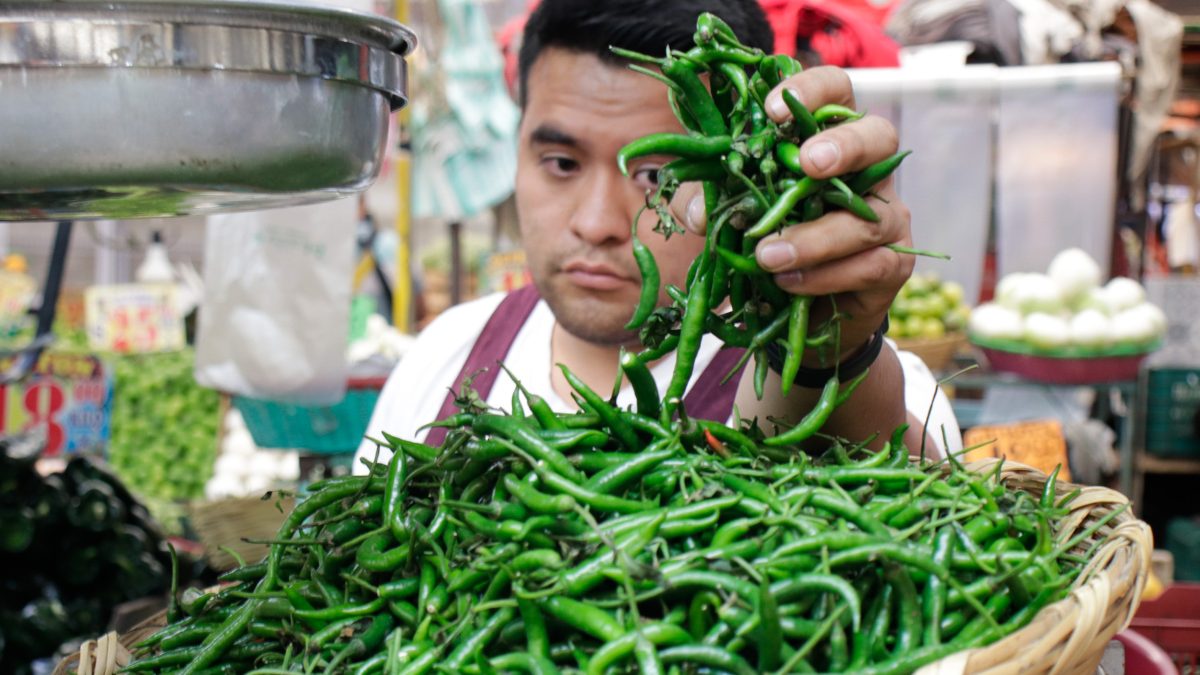 Hombre colocando chiles picantes en una báscula de peso.