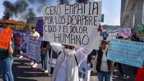 Mujer sostiene una pancarta durante una manifestación en una carretera.