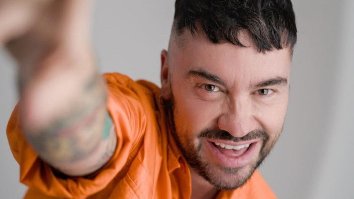 Hombre con camisa naranja, piel apiñonada y ojos claros