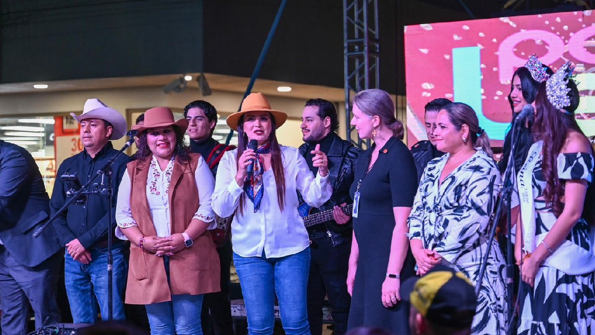 Susy Torrecillas hablando en el festejo del aniversario de Lerdo. Las reinas de la callejoneada, funcionarias y músicos la acompañan en el escenar