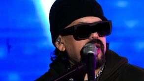Cruz Martínez con lentes oscuros hablando a un micrófono en uno de sus conciertos.